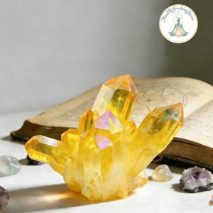 May include: A vibrant yellow aura quartz crystal cluster with iridescent highlights. The cluster features multiple pointed, translucent crystalline structures. A circular logo with the text Mind Refreshing Stone is visible in the upper right corner.