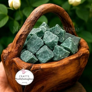 May include: A wooden basket filled with rough-cut, green aventurine stones. The basket has a curved handle and is made of polished wood. The stones are a deep green color and have a slightly rough texture. The basket is labeled "Crafts MindRefreshingStone 2025".