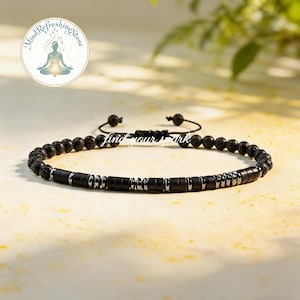 May include: Black beaded bracelet with a sliding knot closure. The bracelet features a mix of round lava stone beads, rectangular black beads, and silver-colored metal accents. The text "find your spark" is visible.