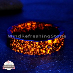Puede incluir: Una pulsera de piedra naranja y azul brillante. La pulsera está hecha de piezas rectangulares de piedra, con una superficie texturizada. El texto "MindRefreshingStone" es visible en la pulsera. La pulsera está sobre una superficie azul oscuro.