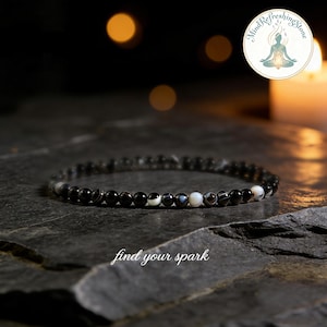 May include: Black and white beaded bracelet with a mix of round and oval beads. The bracelet is displayed on a dark, textured surface. The text "find your spark" is at the bottom of the image.