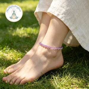 May include: An anklet made of small, round, translucent purple amethyst beads worn around the ankle. The jewelry features a delicate, uniform string of polished stones that catch the light, creating a subtle and consistent purple hue.