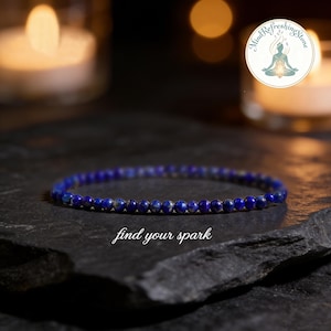 May include: A delicate blue beaded bracelet rests on a dark, textured surface. The bracelet is composed of small, round beads. The phrase "find your spark" is written in cursive below the bracelet. A logo with text and a figure is in the background.