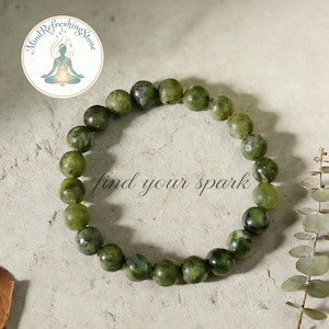 May include: A green jade bead bracelet. The bracelet is made of round, polished beads in varying shades of green. The words "find your spark" are written in cursive script. The image also includes a logo with the words "Mind Refreshing Stone".