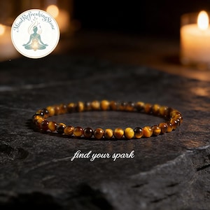 May include: A beaded bracelet made of small, round, tiger's eye stones. The bracelet is a warm brown color with golden and black streaks. The text "find your spark" is written in white script below the bracelet. A logo with text is in the upper left corner.