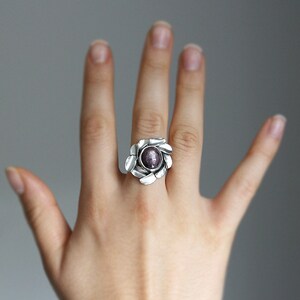 Peut inclure: Une bague en argent avec une pierre pr&eacute;cieuse violette sertie dans un motif en forme de fleur.