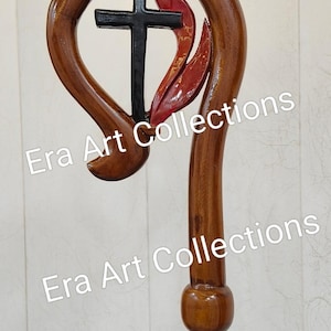 May include: A wooden staff with a curved top featuring a black cross and red flame accents. The staff is a rich brown colour and has the text "Era Art Collections" in the background.