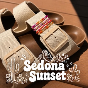 Puede incluir: Un par de sandalias Birkenstock beige con tiras de tela texturizada, que presentan una pila de cuatro pulseras finas de cuentas en tonos rosa, naranja y amarillo. La imagen incluye dibujos lineales blancos de cactus y el texto Sedona Sunset.