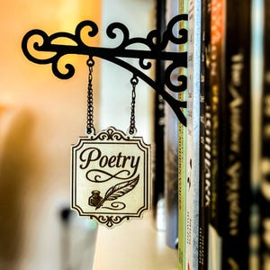 A decorative metal sign with the word "Poetry" hanging from a bookshelf, surrounded by various books.