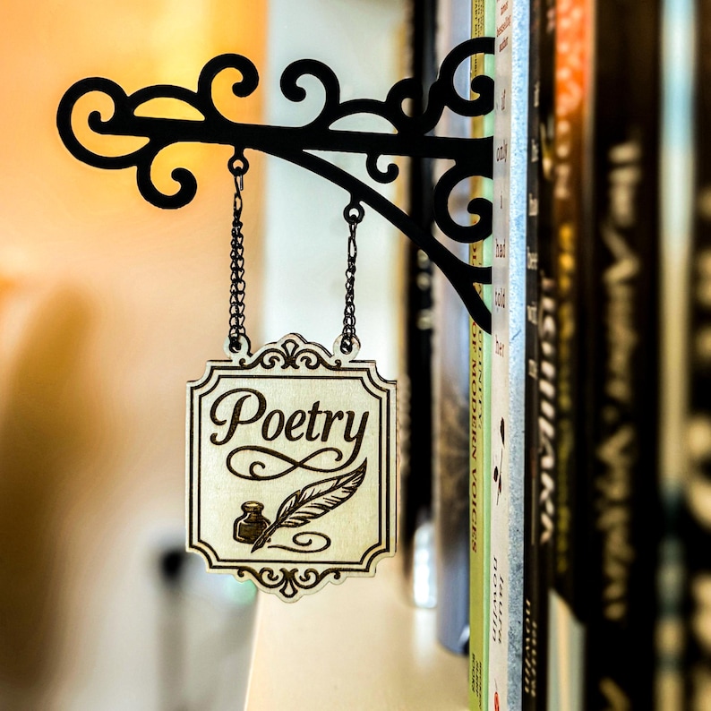 A decorative metal sign with the word "Poetry" hanging from a bookshelf, surrounded by various books.