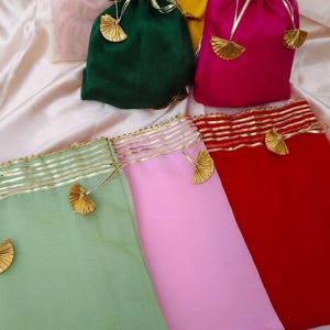 Può includere: Un assortimento di sacchetti colorati con coulisse in varie tonalità, tra cui verde, rosa, giallo e rosso. Ogni sacchetto è adornato con finiture dorate e nappe decorative, suggerendo un tema festivo o regalo.