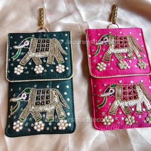 May include: Two decorative phone pouches, one in emerald green and the other in fuchsia. Each pouch features an embroidered elephant design with sequins and beads. They have a rectangular shape with a flap and a gold-colored metal clasp.
