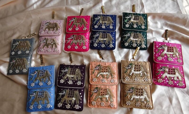 May include: A collection of colorful, rectangular, small purses with a flap closure. Each purse features an embroidered elephant design with gold and silver accents. The purses come in various colors, including pink, blue, and green.