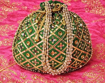May include: A green, round, beaded pouch with a drawstring closure. The pouch is decorated with gold accents and a diamond pattern. A strand of white pearls hangs from the top. The pouch is set against a pink background.