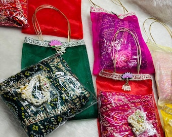 May include: A collection of colorful, sheer fabric bags with gold handles. The bags are in various colors, including red, green, and pink, and are decorated with floral accents and lace trim. Some bags contain jewelry.