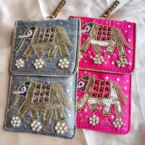 May include: Two embellished phone pouches, one gray and one pink, with gold elephant designs. The elephants are adorned with sequins and beads. Each pouch has a gold-tone clasp and a small floral embellishment.
