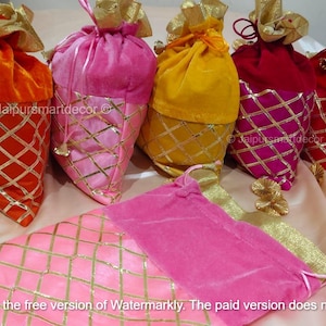 May include: A collection of colorful velvet pouches in orange, pink, yellow, and red, with gold diamond-patterned accents. Each pouch has a drawstring closure and gold trim. The pouches are arranged on a light-colored fabric.