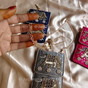May include: Embroidered small purses in blue, gray, and pink, featuring elephant designs with gold sequins and pearl accents. Each purse has a chain strap. The image includes the text "Jaipursmartdecor".