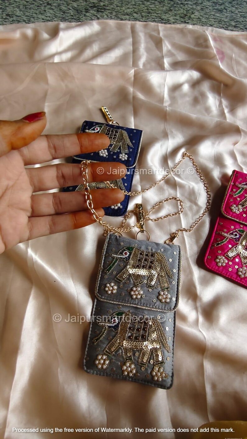 May include: Embroidered small purses in blue, gray, and pink, featuring elephant designs with gold sequins and pearl accents. Each purse has a chain strap. The image includes the text "Jaipursmartdecor".