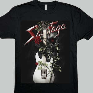 May include: A black short-sleeve t-shirt featuring a graphic print of a white electric guitar intertwined with red roses and thorny vines in front of a dark skull with glowing red eyes. The word Savage is printed in a stylized red and white font.