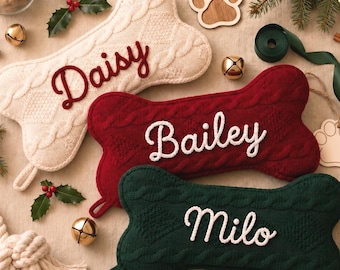 May include: Three bone-shaped pet stockings made of cable-knit fabric in cream, dark red, and dark green. Each stocking features a personalized name embroidered in a contrasting color: Daisy in red, Bailey in white, and Milo in white.