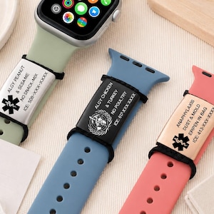 Könnte beinhalten: Drei Smartwatch-Armbänder aus Silikon in Salbeigrün, Staubblau und Korallenrosa. Jedes Armband hat ein rechteckiges medizinisches Warnschild, das mit schwarzen Gummischlaufen befestigt ist und mit Allergieinformationen, dem Star of Life-Symbol und ICE-Nummern graviert ist.