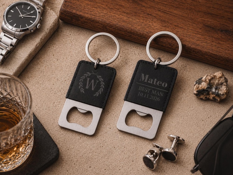 May include: Two rectangular black leather keychains with integrated silver-tone metal bottle openers. One keychain features a laurel wreath design with the letter W, while the other is engraved with the text Mateo, BEST MAN, and 10.11.2026.