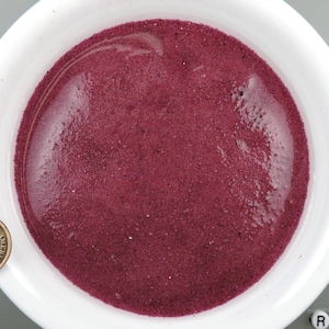 Puede incluir: Un bol blanco lleno de arena fina de color rojo oscuro.