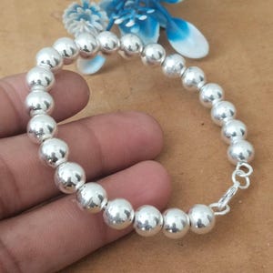 May include: A silver bracelet featuring a series of round, polished beads. The bracelet is secured with a small clasp. The beads are approximately 0.4 inches in diameter. The bracelet is displayed against a neutral background.