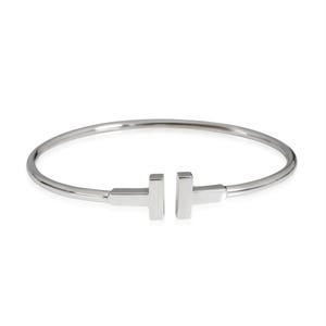 May include: A polished silver-tone metal cuff bracelet featuring a smooth, rounded band that terminates in two T-shaped ends facing each other at the centre opening. The design is clean and metallic with a reflective surface throughout the piece.