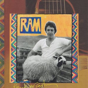 May include: A CD and DVD collector's edition of Paul McCartney's "Ram" album. The cover features a photo of a man with a sheep, the word "RAM" in blue and yellow, and the text "ALTERNATE ARCHIVE COLLECTION".