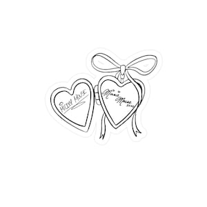 Op de afbeelding: Een zwart-witte sticker met twee hartvormige medaillons. Op het ene medaillon staat "Mickey Mouse" en op het andere "Minnie Mouse xoxo". Bovenop de medaillons bevinden zich een strik en een lint.