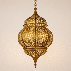 May include: A gold-toned metal pendant light fixture featuring an intricate, laser-cut filigree pattern with geometric floral motifs. The lantern has a bulbous, multi-tiered shape with a pointed base and is suspended by a matching metal chain.