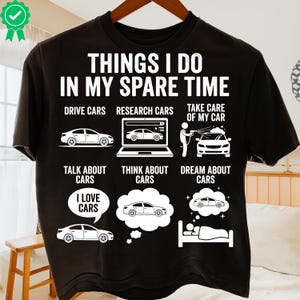 May include: Black t-shirt featuring white text and car-related illustrations. The shirt's text reads "THINGS I DO IN MY SPARE TIME", with images depicting driving, researching, and dreaming about cars.