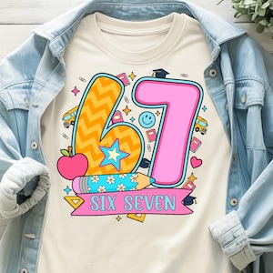 May include: Cream-colored t-shirt featuring a colorful graphic design for a sixth or seventh birthday. The design includes the numbers "6" and "7", a pencil, an apple, and the words "SIX SEVEN" on a banner.