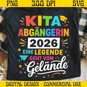 May include: Black t-shirt with the German text "KITA ABGÄNGERIN 2026 EINE LEGENDE GEHT VOM Gelände." The design features a graduation cap, stars, and a paper airplane in vibrant colors. The text is in red, orange, yellow, green, and blue.