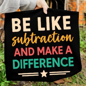 Könnte beinhalten: Schwarze Tragetasche mit dem Text "BE LIKE subtraction AND MAKE A DIFFERENCE" in verschiedenen Farben. Der Text ist in einer verspielten Schriftart gehalten. Die Tasche hat auch einen Stern und zwei horizontale Linien.