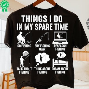 Pode incluir: Camiseta preta com o texto "THINGS I DO IN MY SPARE TIME" e ilustrações relacionadas à pesca. O design inclui imagens de pesca, compra de equipamentos, pesquisa, conversa, pensamento e sonho sobre pesca.