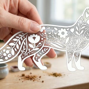 Peut inclure: Une silhouette de renard découpée présentant un motif floral et botanique blanc complexe sur un fond semi-transparent. Le design comprend des fleurs, des feuilles et des baies stylisées intégrées dans la forme du corps du renard.