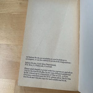 May include: Open book page with text. The text reads: "All Sphere Books are available at your bookshop or newsagent, or can be ordered from the following address: Sphere Books, Cash Sales Department, P.O. Box 11, Falmouth, Cornwall."