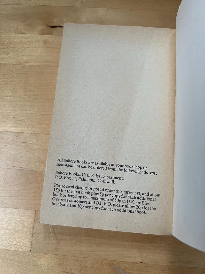 May include: Open book page with text. The text reads: "All Sphere Books are available at your bookshop or newsagent, or can be ordered from the following address: Sphere Books, Cash Sales Department, P.O. Box 11, Falmouth, Cornwall."