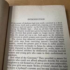May include: Open book page with text titled "INTRODUCTION". The text is in black font on aged, off-white paper. The page is slightly angled, showing the top and side edges. The text discusses historical views on demons, the church, and convents.