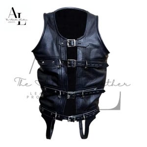 Op de afbeelding: Zwart leren vest met meerdere verstelbare riemen en gespen. Het vest heeft een mouwloos ontwerp en een hoge halslijn. Het product is van The Adelle Leather.
