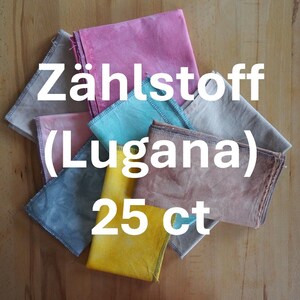 Puede incluir: Una colección de cuadrados de tela coloridos en tonos rosa, azul, amarillo y gris. El texto "Zählstoff (Lugana) 25 ct" se muestra en blanco. Las telas están dispuestas sobre una superficie de madera.