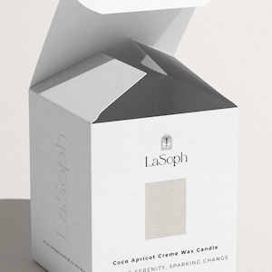 May include: A white cardboard box with an open top flap. The front features the black text LaSoph, a small arch icon, the words Coco Apricot Creme Wax Candle, LIGHTING SERENITY, SPARKING CHANGE, and 8OZ. The side displays the text LaSoph vertically.