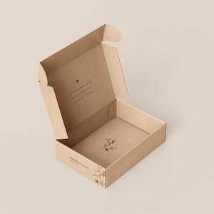 May include: A light brown cardboard shipping box with an open lid. The exterior features the text meadowsweet and a small botanical illustration. The interior base has a floral graphic, and the inside lid contains printed text and a small flower icon.