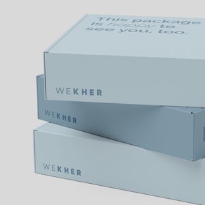 May include: A stack of three light blue rectangular cardboard shipping boxes. Each box features the brand name WEKHER printed in dark blue on the front side. The top box has the text This package is happy to see you, too. printed on its lid.