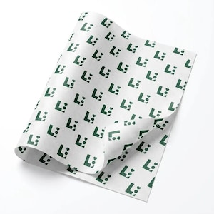 May include: A sheet of white tissue paper featuring a repeating pattern of dark green logos. Each logo consists of a capital letter L, a small solid circle, and a small heart shape arranged in a compact, geometric formation across the surface.