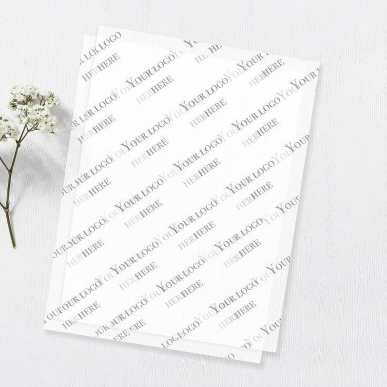 May include: A stack of translucent white tissue paper sheets featuring a repeating diagonal pattern of the grey text YOUR LOGO HERE. The paper is thin and semi-transparent, displaying the repeated branding text across the entire surface area.