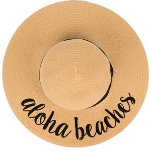 May include: A straw sun hat with a black ribbon and the text "Aloha Beaches" embroidered on the brim.